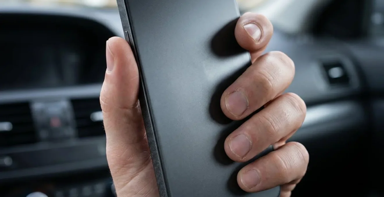 Mains tenant un smartphone avec une application de navigation pour bornes de recharge électrique affichée