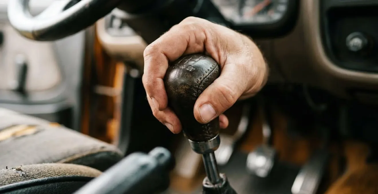 Main sur le levier de vitesse testant l'embrayage d'une voiture d'occasion